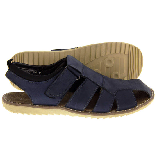 Mens leather sandals. Classic sandal with a navy blue leather upper. Closed toe but with straps to give a cut outs down the side to keep feet cool. Touch close fastening ankle strap. With a brown insole and sand coloured outsole. Both feet together at a slight angle. Both feet from a side profile with left foot behind the right on its side to show the sole.