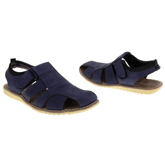 Mens leather sandals. Classic sandal with a navy blue leather upper. Closed toe but with straps to give a cut outs down the side to keep feet cool. Touch close fastening ankle strap. With a brown insole and sand coloured outsole. Both feet at an angle facing top to tail.