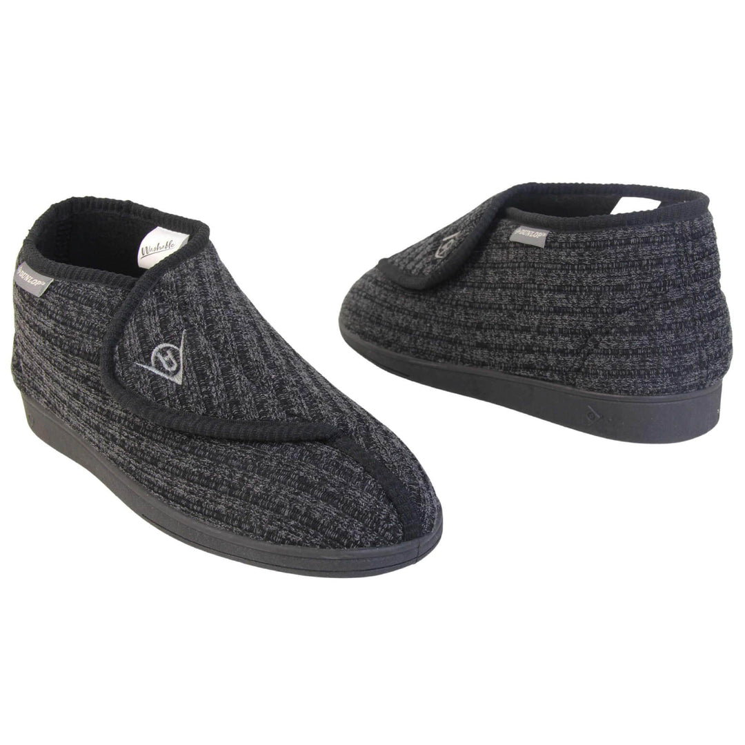 Orthopaedic slippers for men. Mens orthopaedic slippers in an ankle boot style. With a black knit upper and black fleece lining. With an adjustable touch close top with a grey Dunlop logo on. Small grey label to the outer side edge with Dunlop written on. Thick black outdoor sole.  Both feet at an angle facing top to tail.