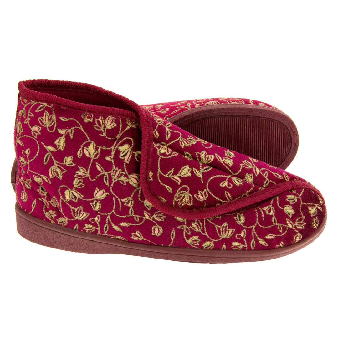 Ankle boot slippers. Womens bootie style slipper with a burgundy textile upper with vine and flower embroidered design and red edging. Touch fasten tab to the top and red textile lining. Firm red sole.  Both feet from a side profile with the left foot on its side behind the the right foot to show the sole.