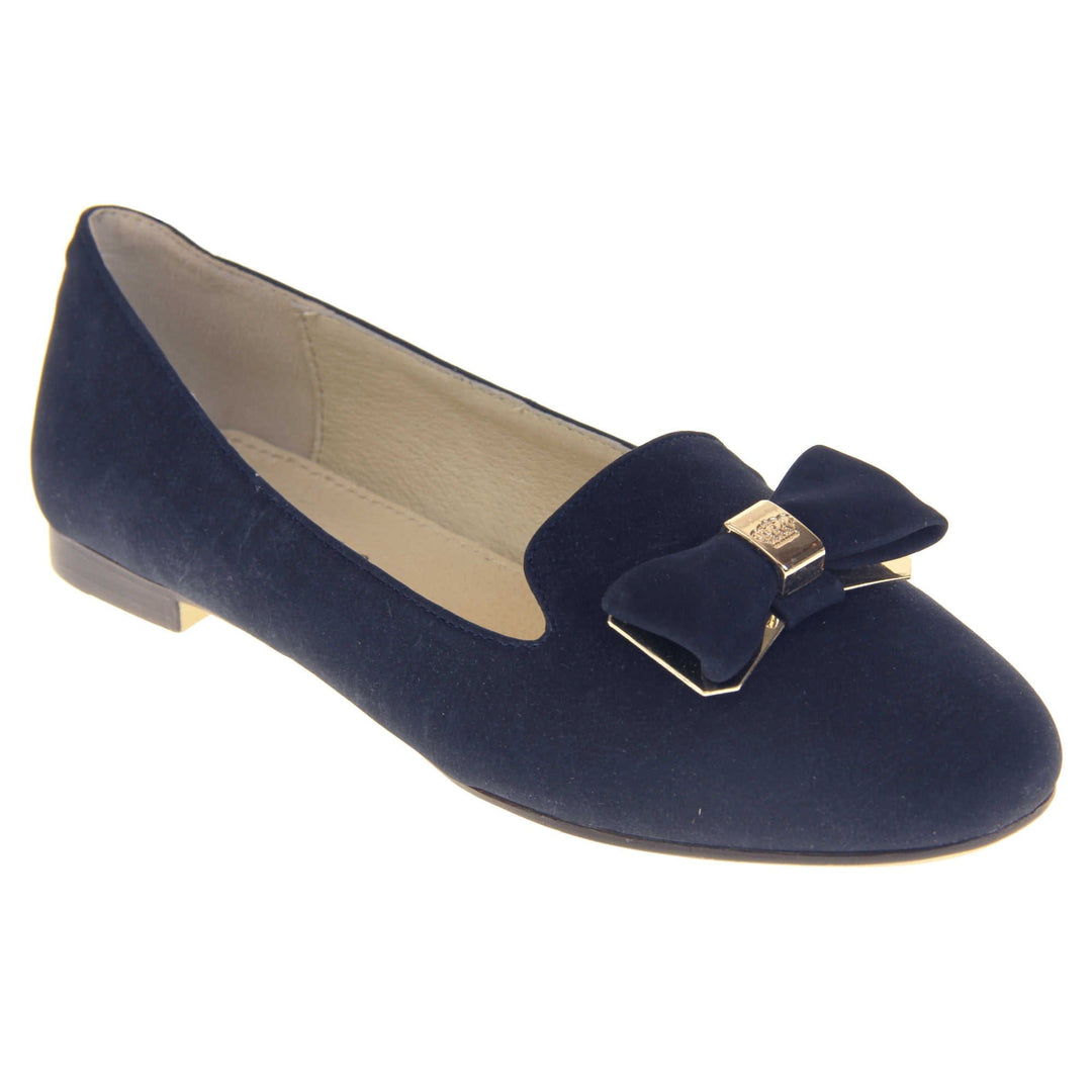 Ballet loafer. Women's shoe in a ballerina style loafer with a navy faux suede upper. Dark blue bow with gold coloured metal backing and middle. Brown sole with beige bottom with very small heel. Cream leather lining. Right foot at an angle.