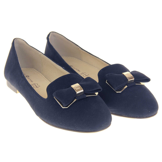 Ballet loafer. Women's shoe in a ballerina style loafer with a navy faux suede upper. Dark blue bow with gold coloured metal backing and middle. Brown sole with beige bottom with very small heel. Cream leather lining. Both feet together at a slight angle.