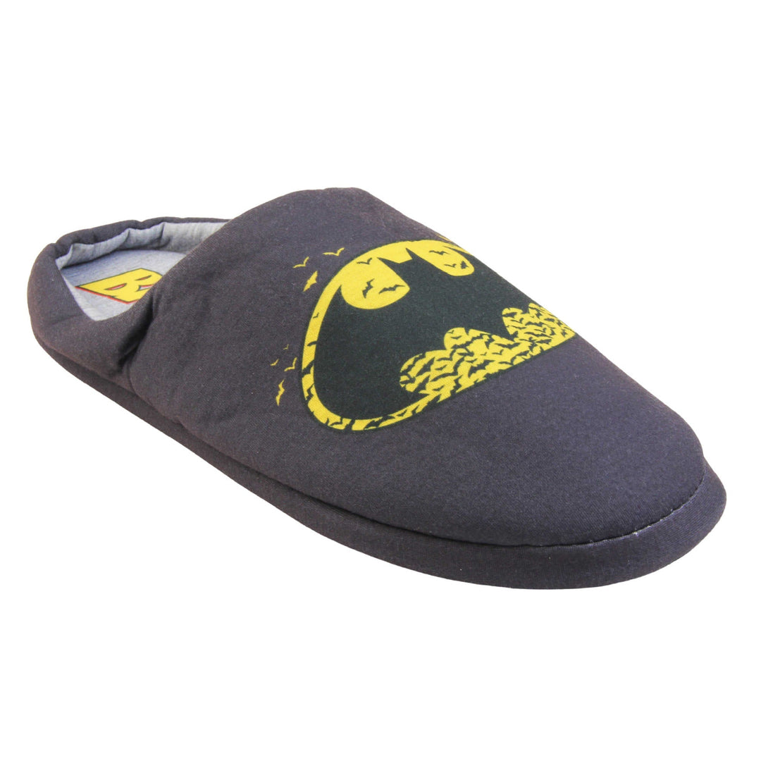 Batman slippers mens. Mule style slippers with black textile upper with a yellow Batman logo on the top. Grey textile lining and firm black sole. Right foot at an angle.