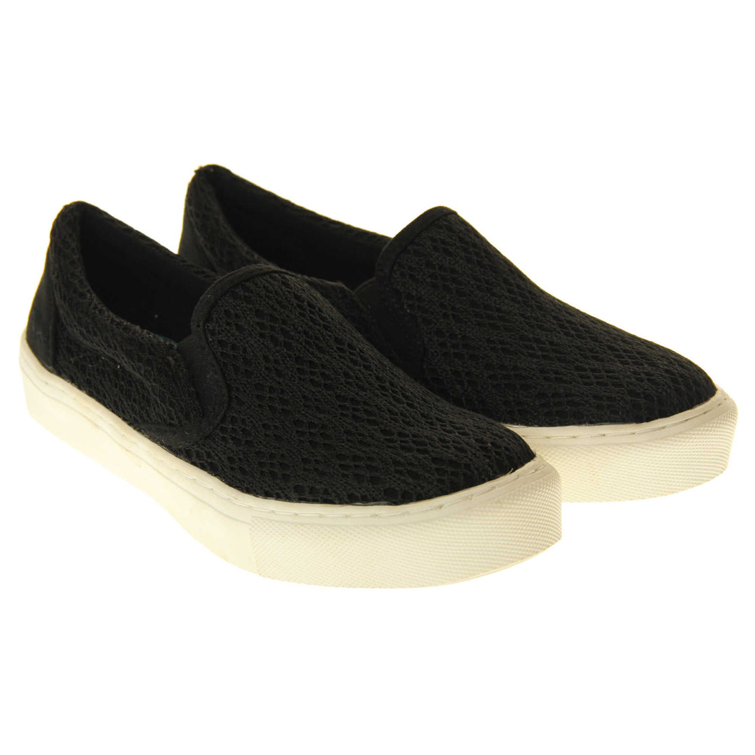 Black crochet shoes. Slip on plimsoll style shoes with a black canvas upper with a crochet overlay. Black elasticated gusset. White flat platform sole. Both feet together at a slight angle.