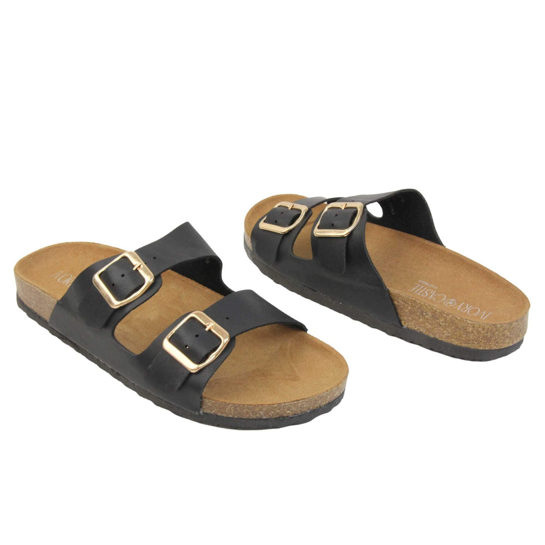 Black double strap sandals. Womens dual strap slip on sandals. With a black synthetic leather upper with a gold buckle on each strap. Brown faux suede insole with a moulded footbed. Cork effect outsole with black base with grip to the bottom. Both feet at an angle facing top to tail.