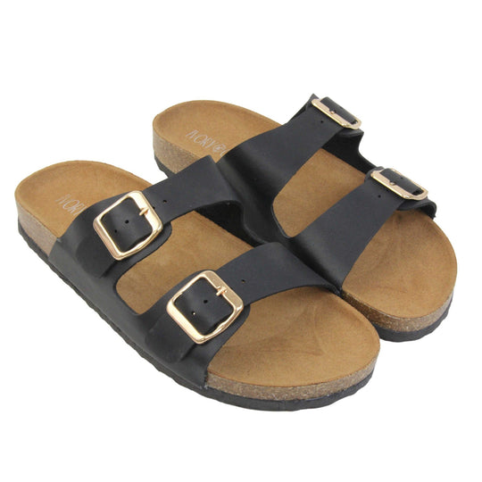 Black double strap sandals. Womens dual strap slip on sandals. With a black synthetic leather upper with a gold buckle on each strap. Brown faux suede insole with a moulded footbed. Cork effect outsole with black base with grip to the bottom. Both feet together at a slight angle.