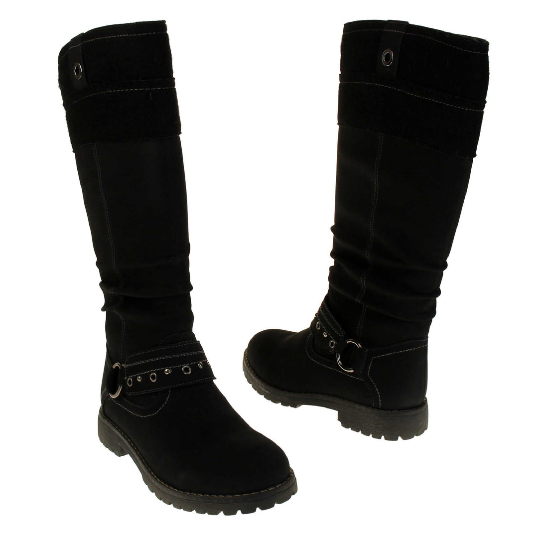 Black faux nubuck knee high boot. Tall boots with a black faux nubuck leather upper with a felt decorative cuff around the top. A strap with stud embellishment goes around the front of the ankle connected by a silver loop. Stitching detail around the outsole and the ankle. Full length zip to the inside leg. Both feet from a slight angle facing top to tail.