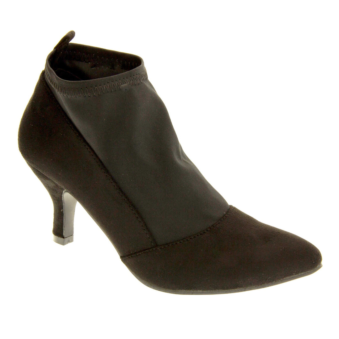 Black faux suede ankle boots. Womens black faux suede ankle boot with a stretchy black fabric panel to the front and around the top of the ankle. Small faux suede loop to the back for pulling onto your feet. Small black faux suede heel and black sole. Right foot at an angle.