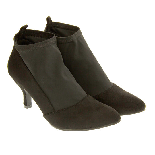 Black faux suede ankle boots. Womens black faux suede ankle boot with a stretchy black fabric panel to the front and around the top of the ankle. Small faux suede loop to the back for pulling onto your feet. Small black faux suede heel and black sole. Both feet together at a slight angle.