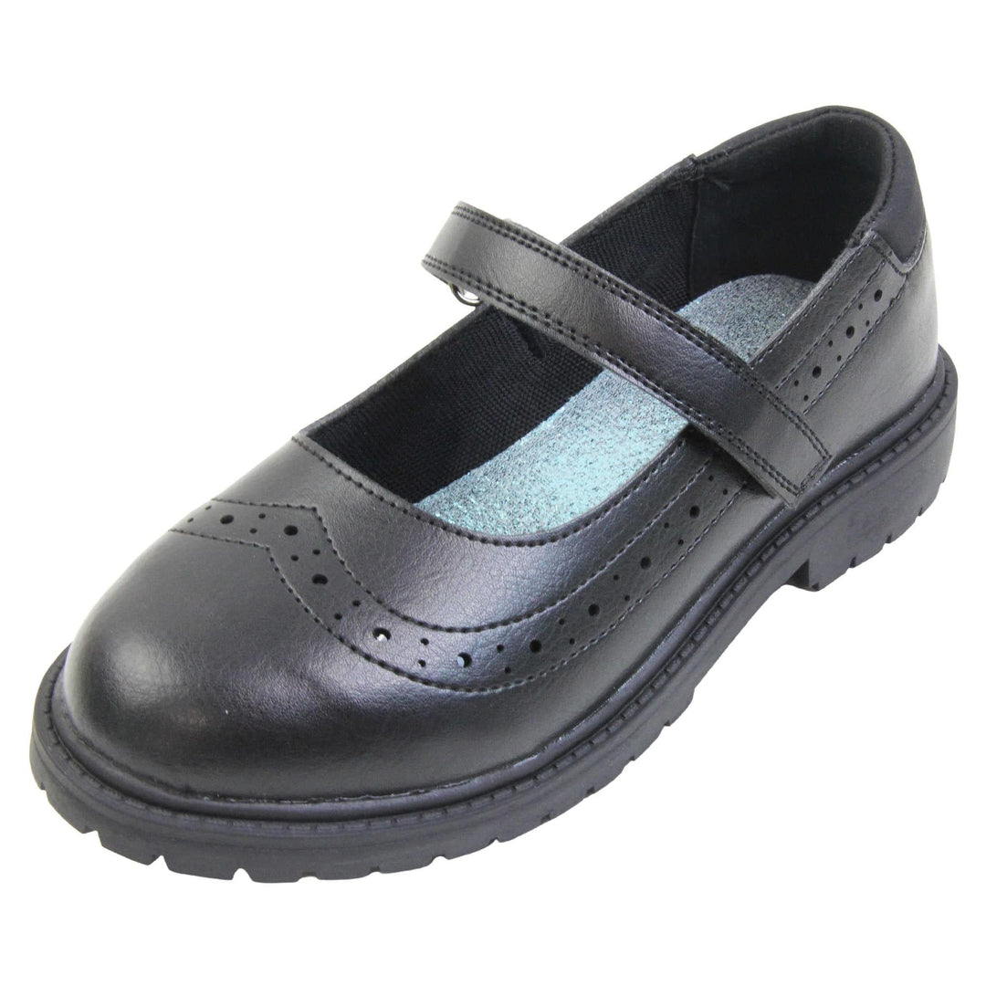 Black school shoes for teenage girls. Mary Jane style shoes with black faux leather uppers. With a touch fasten strap over the foot and brogue detailing around the top of the shoe. Black textile lining with a metallic blue insole. Chunky black sole with slight heel. Left foot at an angle.