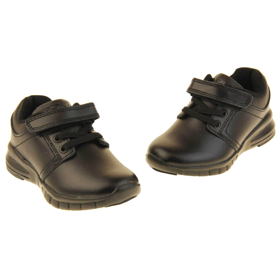 Black School Shoes. Matt black coated leather trainer shoes. With black sole and elasticated lace detailing and touch fastening strap to the top. Both shoes with toes pointing in a v.