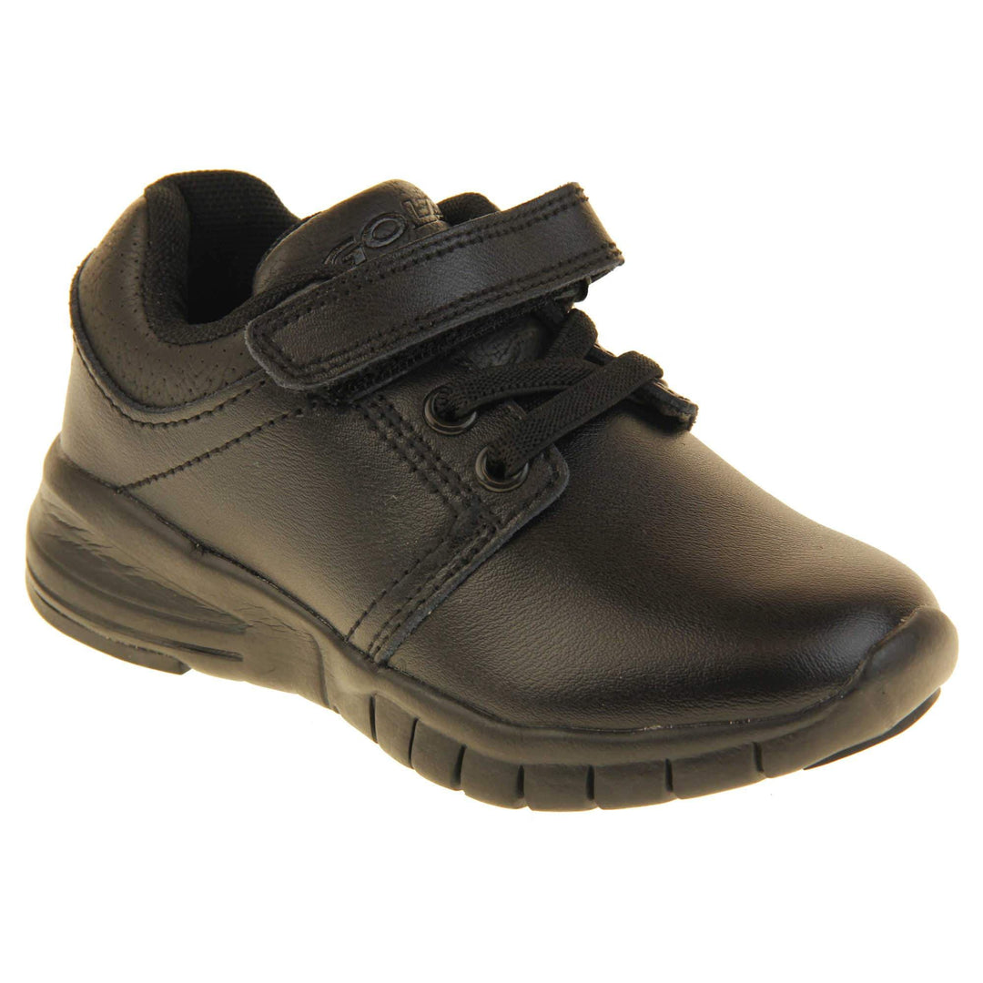 Black School Shoes. Matt black coated leather trainer shoes. With black sole and elasticated lace detailing and touch fastening strap to the top. Right foot at an angle