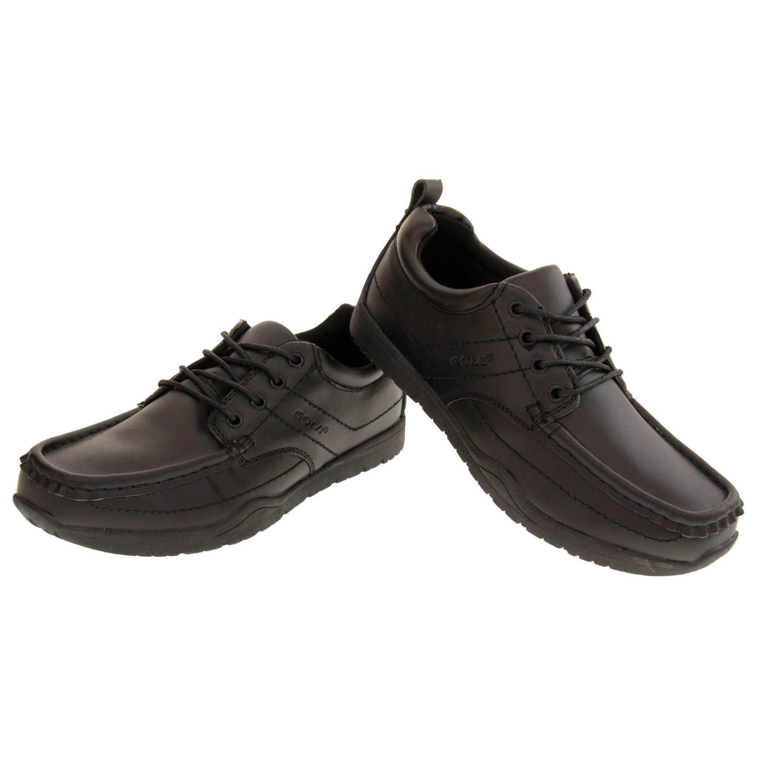 Black school shoes. Gola black leather school shoes, similar to trainer style. With stitched detailing and Gola branding embossed into the side. With black laces and a black loop on the heel to help pull the on. Black sole with good grip. Both feet in a wide V shape with right foot heel on top of the left heel to lift it slightly.