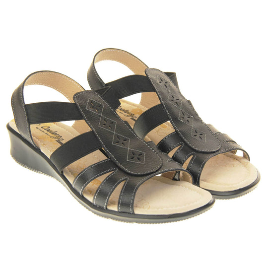 Black slingbacks. Classic womens slingback sandals with black faux leather straps. Cut out detailing to the centre strap. Two elasticated straps either side of the foot meeting the centre strap. Beige faux leather cushioned insoles. Small cream wedge outsole. Both shoes together from an angle