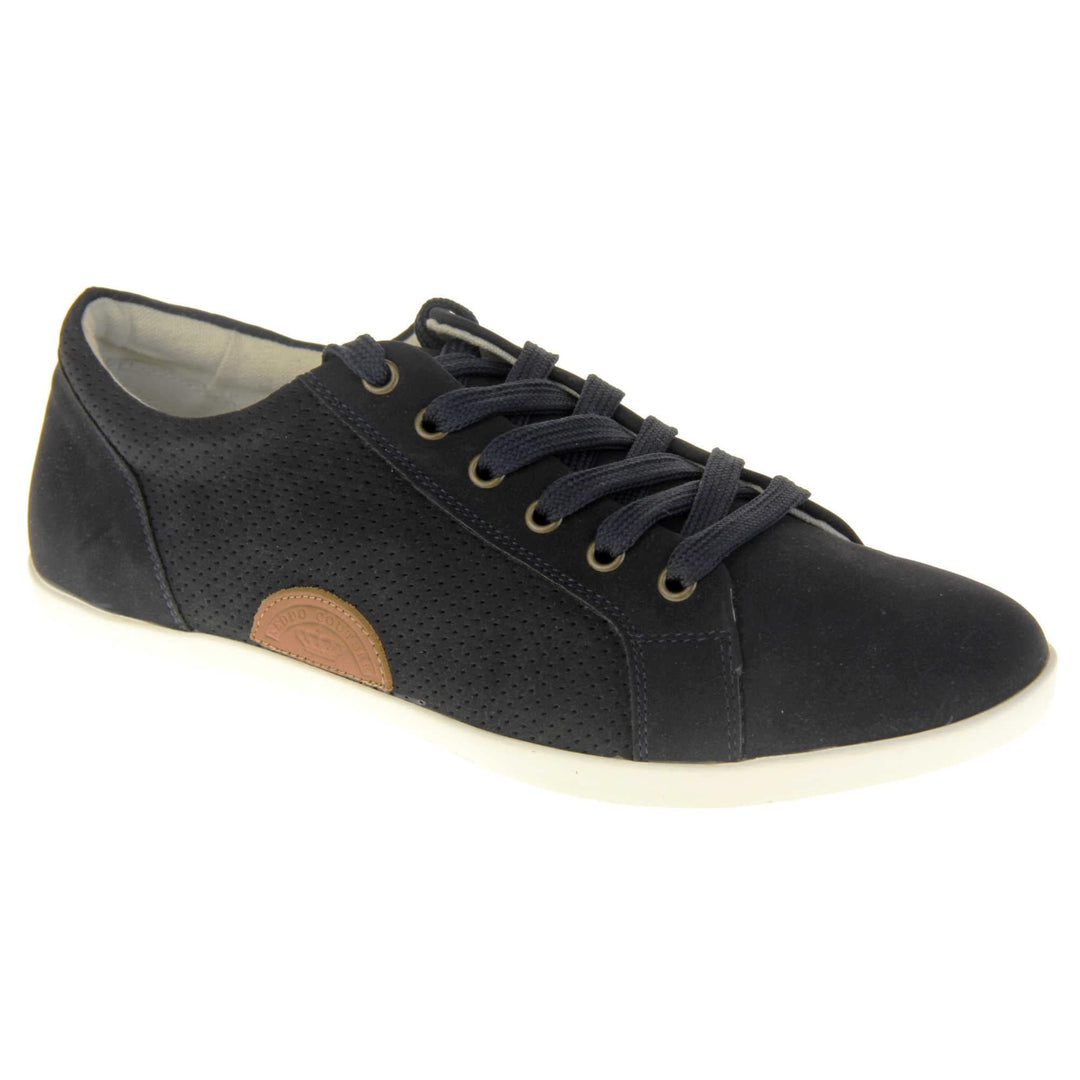 Black suede trainers. Women's shoes in a sneaker style with a black faux suede upper. Tiny dot cut-out detailing to the side of the shoe. Black laces and a brown half-circle to the side of the shoe with Keddo branding on it. White leather lining and sole. Right foot at an angle.