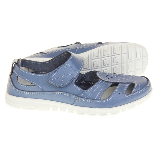 Blue wide fit sandals. Mary Jane style shoes. Blue leather uppers with white stitching detail. Blue touch fasten strap over the foot. Cut outs in the middle, edges and heel of the shoes. White sole with grip to the bottom.  Both feet from a side profile with left foot on its side behind the right to show the sole.