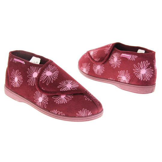 Boot slippers with hard sole. Womens bootie style slipper with a burgundy textile upper with a pink flower print. Touch fasten tab to the top and red textile lining. Firm red sole. Both feet at an angle, facing top to tail.