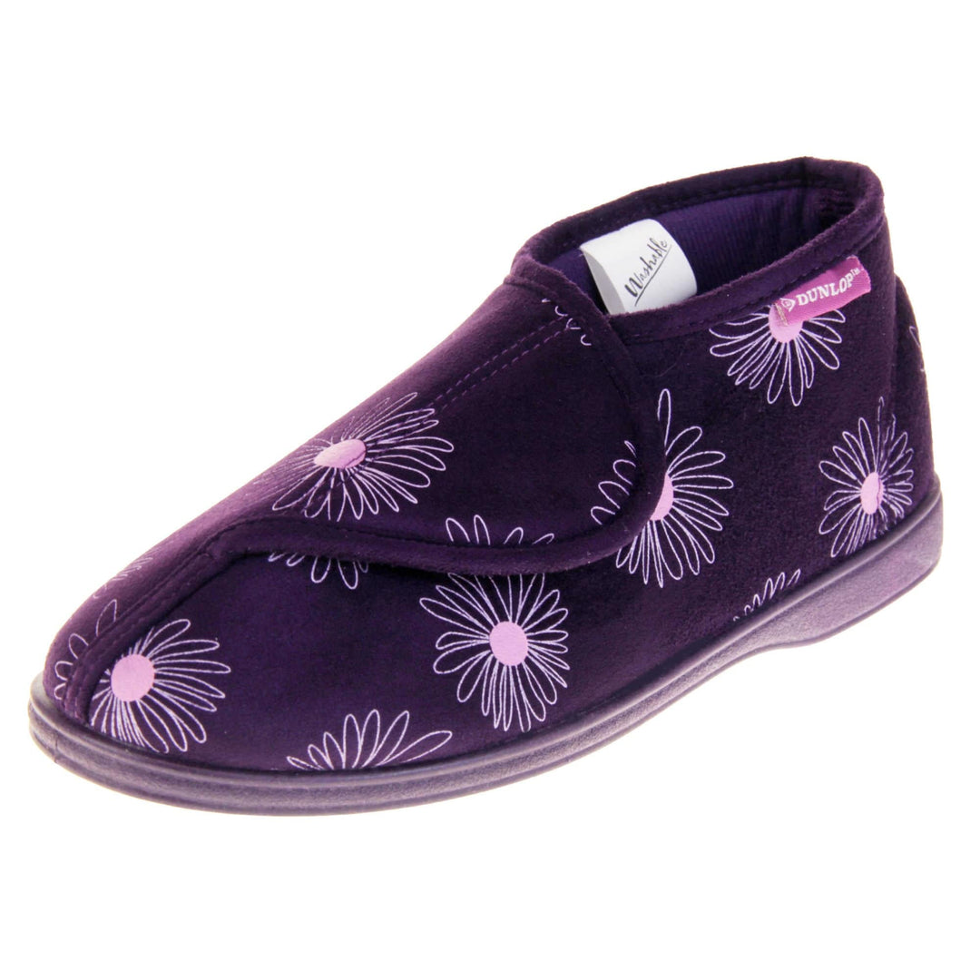 Bootie slippers. Womens bootie style slipper with a purple textile upper with a pink flower print. Touch fasten tab to the top and purple textile lining. Firm purple sole. Left foot at an angle.