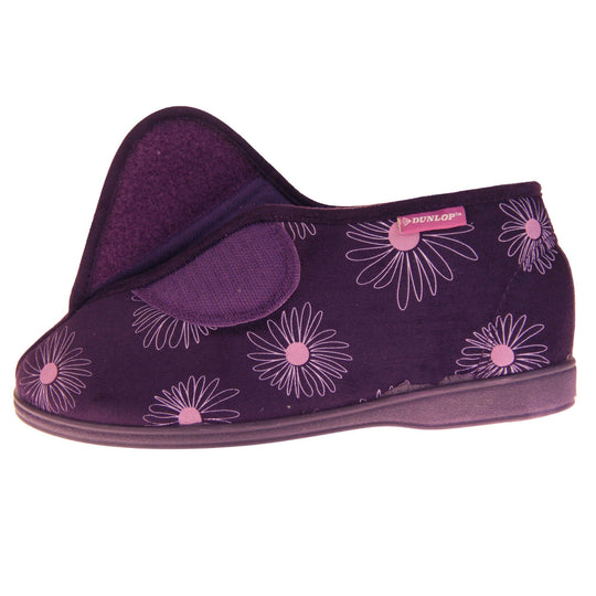 Bootie slippers. Womens bootie style slipper with a purple textile upper with a pink flower print. Touch fasten tab to the top and purple textile lining. Firm purple sole. Left foot from a side view with the touch fasten tab open.