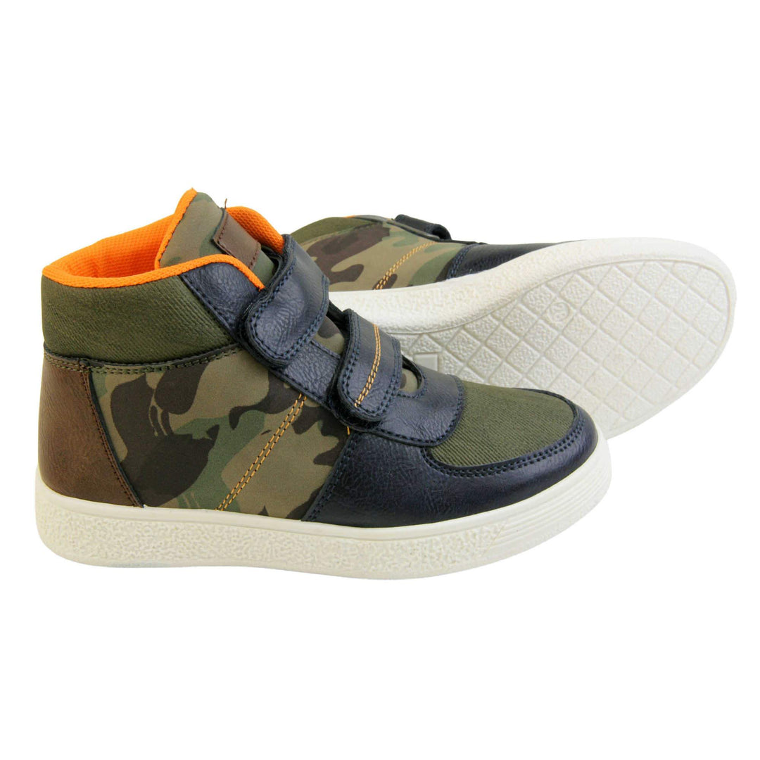 Boots for Boys. Boys canvas ankle boots with camouflage sides and tongue, khaki collar and upper toes and navy faux leather edging details. Touch fasten straps to the front with a white sole. Both feet with the left foot on its side showing the sole.
