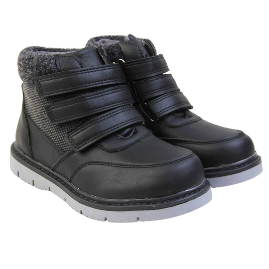 Boys Ankle Boots. Black faux leather upper with textile side panels and black faux fur collar. Three black touch fasten faux leather straps along the front. Grey synthetic sole with grip to the base. Both feet together at an angle.