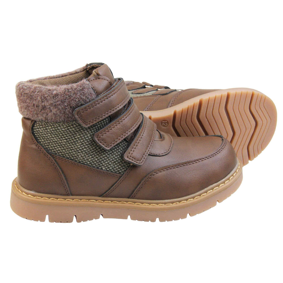 Boys Ankle Boots. Brown faux leather upper with textile side panels and brown faux fur collar. three brown touch fasten faux leather straps along the front to fasten boot. Tan coloured synthetic sole with grip to the base. Both feet from a side profile with left foot on its side to show the sole.