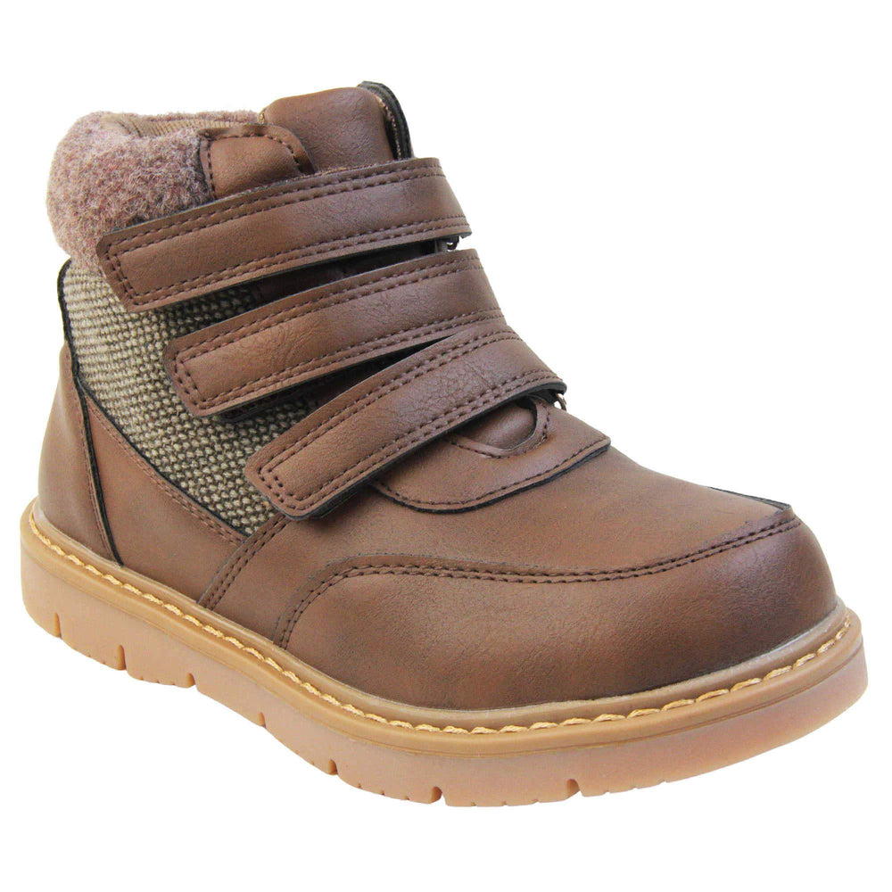 Boys Ankle Boots. Brown faux leather upper with textile side panels and brown faux fur collar. three brown touch fasten faux leather straps along the front to fasten boot. Tan coloured synthetic sole with grip to the base. Right foot at an angle.