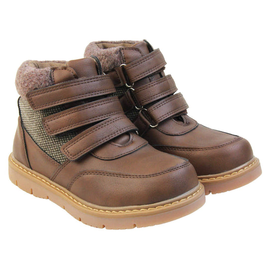 Boys Ankle Boots. Brown faux leather upper with textile side panels and brown faux fur collar. three brown touch fasten faux leather straps along the front to fasten boot. Tan coloured synthetic sole with grip to the base. Both feet together at an angle.