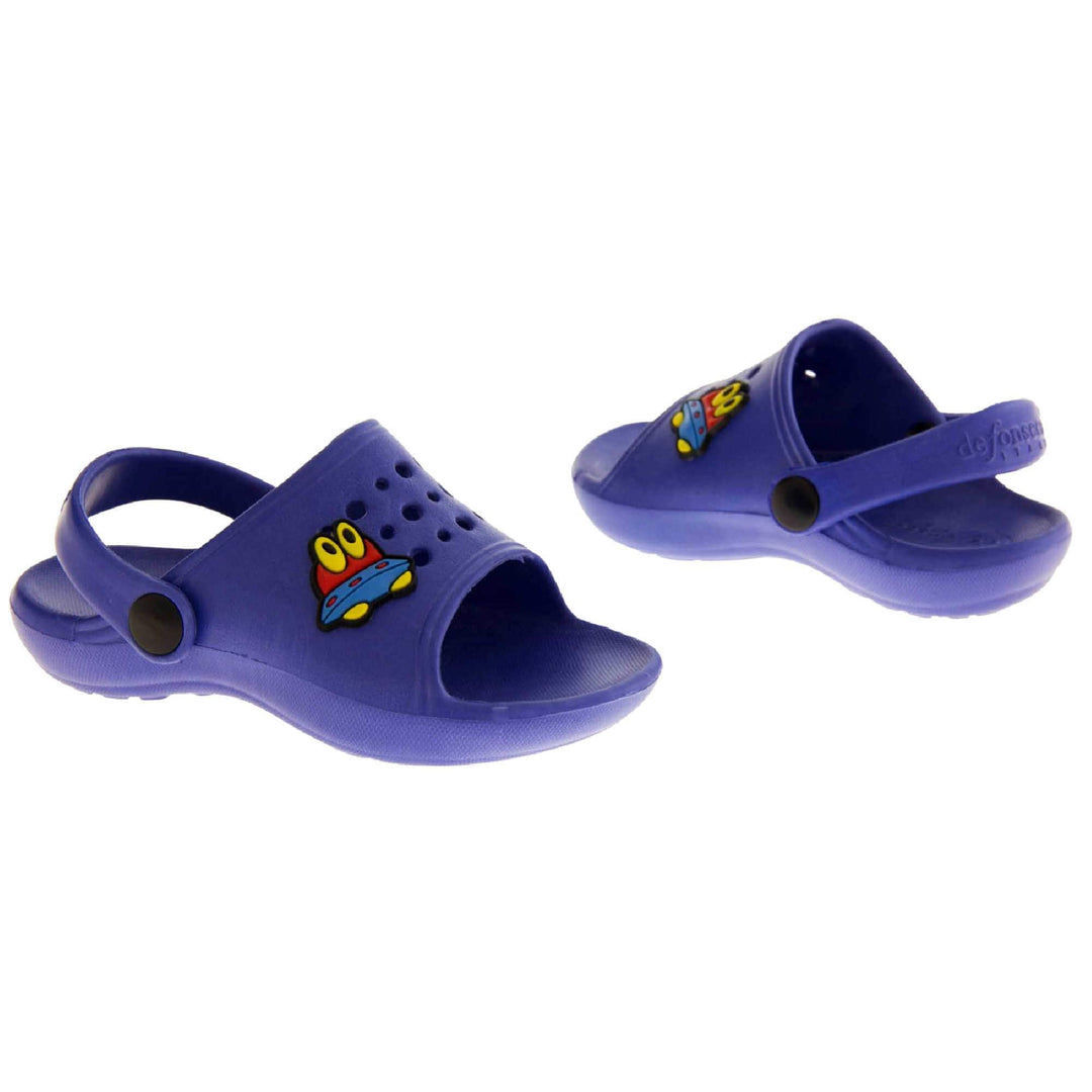 Boys Clogs. Blue synthetic clog style shoes. Open toed with cut out holes in the upper with alien detail just off centre. Blue strap that goes along the back of your heel. The strap can be moved along the top of the shoe instead to make the shoe a mule. Both shoes at an angle facing top to tail.