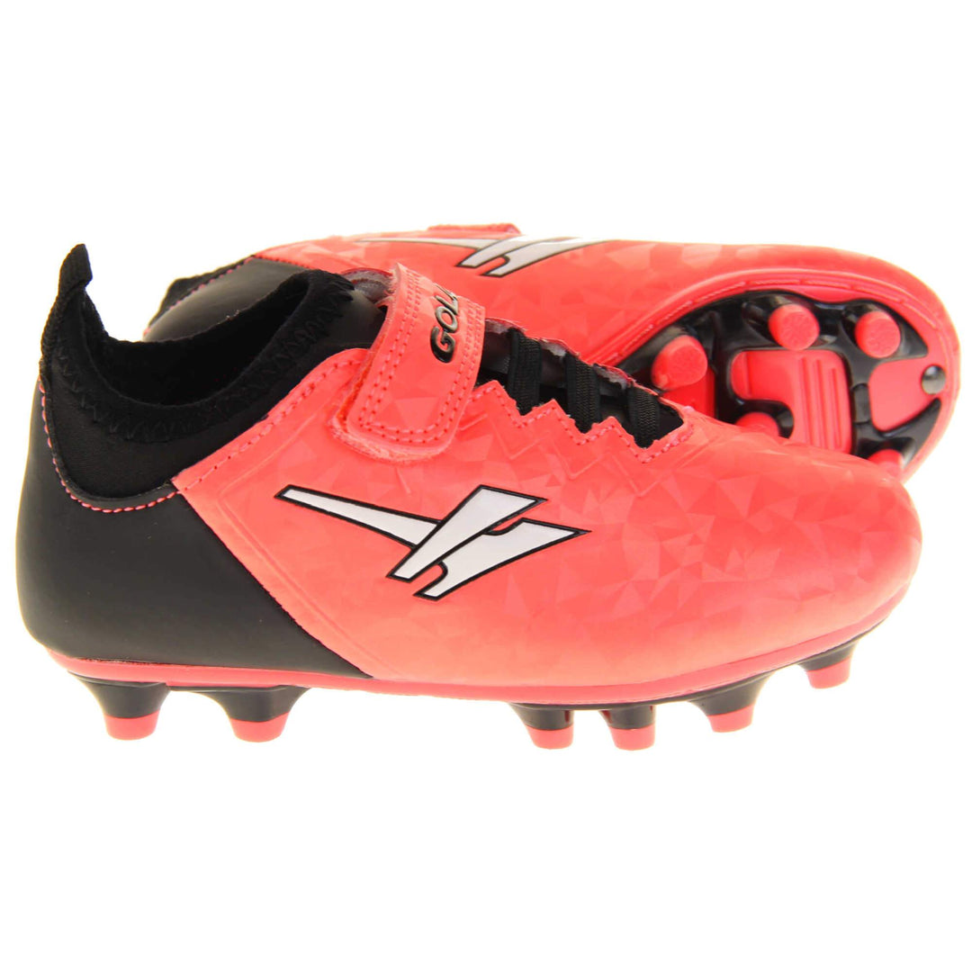 Kids football boots. Metallic red Gola boots with white Gola logo to the sides. With black heel, tongue and black elastic lace detail to the front. Red touch close strap with Gola branding across it. Black sole with red accents and studs. Both feet from side profile with the left foot on its side to show the sole.