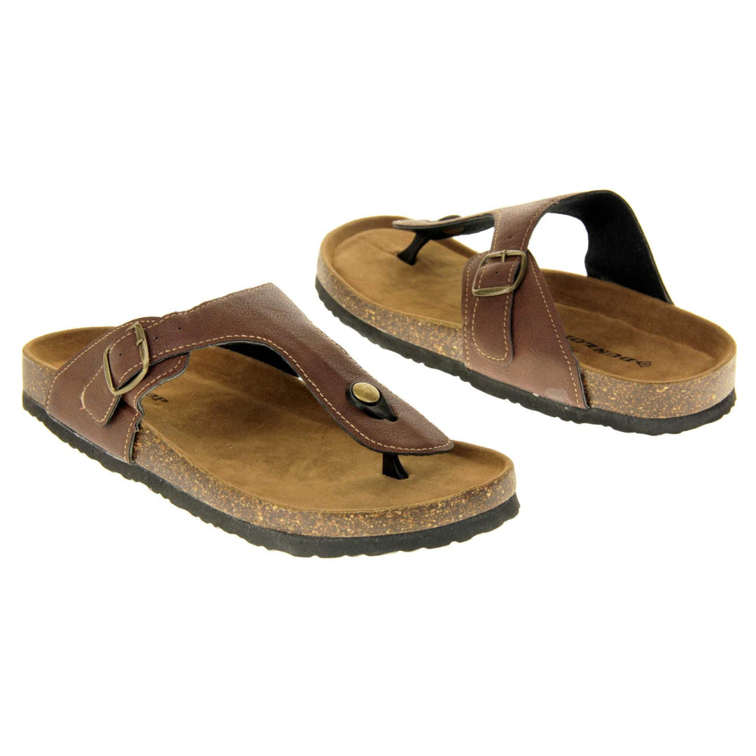 Brown buckle sandals. Dark brown faux leather strap with toe post to the front and gold buckle to the outside. Soft tan faux suede footbed with cork effect outsole and black sole. Both feet at an angle facing top to tail.