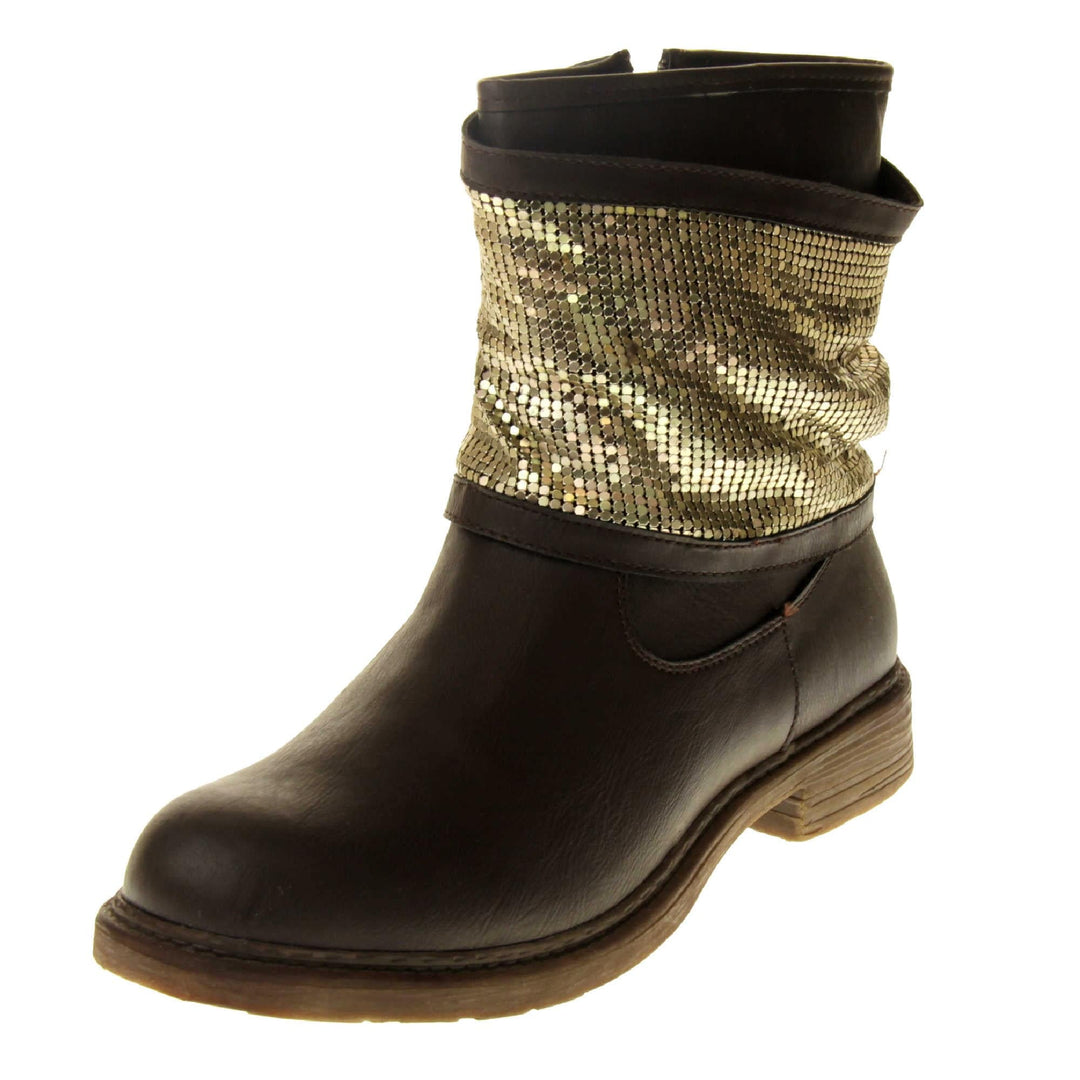 Brown faux leather ankle boots. Biker style boots with a dark brown upper. A thick band of shiny gold chainmail runs around the ankle. Zip fastening down the inside of the boot. Brown sole with a slight heel. Left foot at an angle.