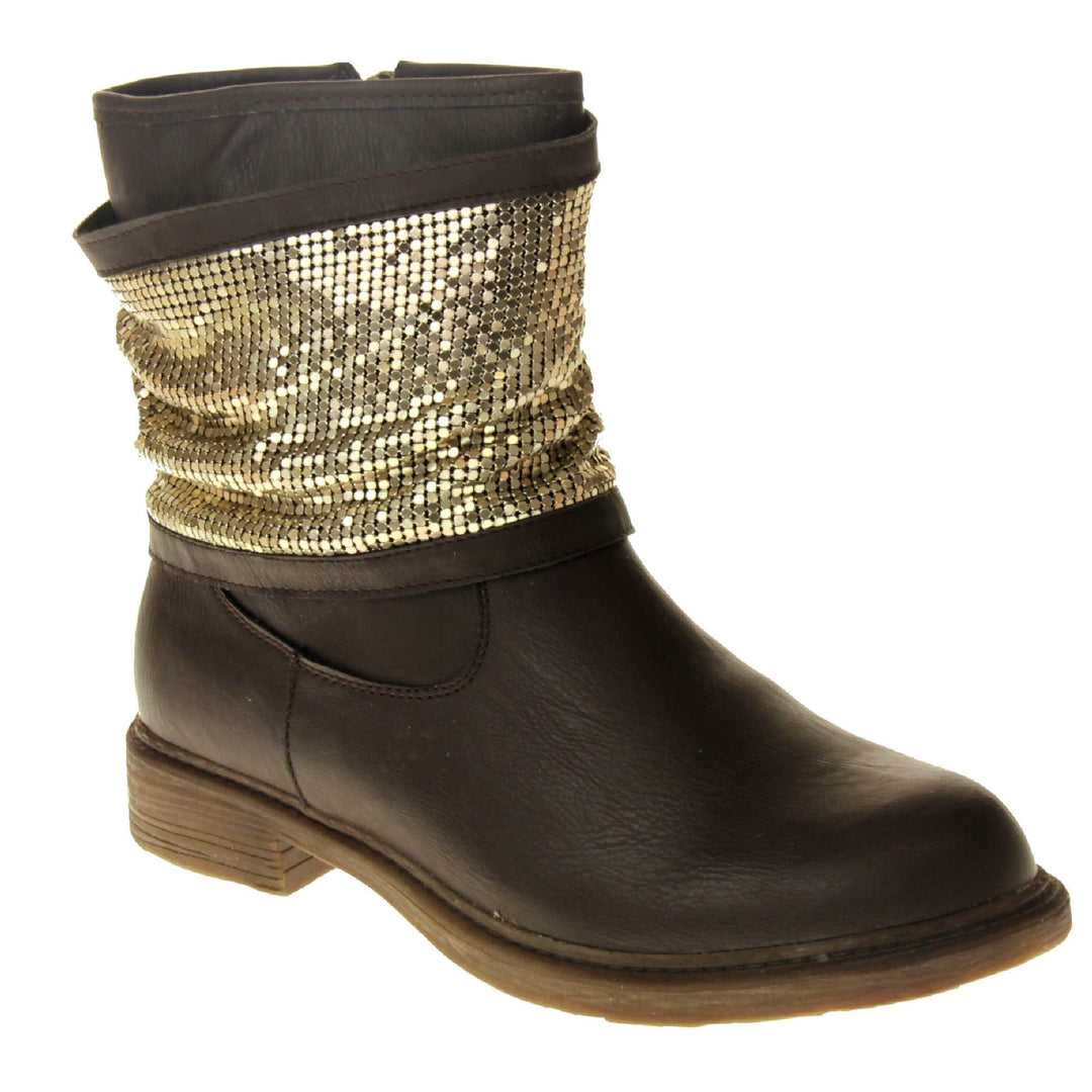 Brown faux leather ankle boots. Biker style boots with a dark brown upper. A thick band of shiny gold chainmail runs around the ankle. Zip fastening down the inside of the boot. Brown sole with a slight heel. Right foot at an angle.