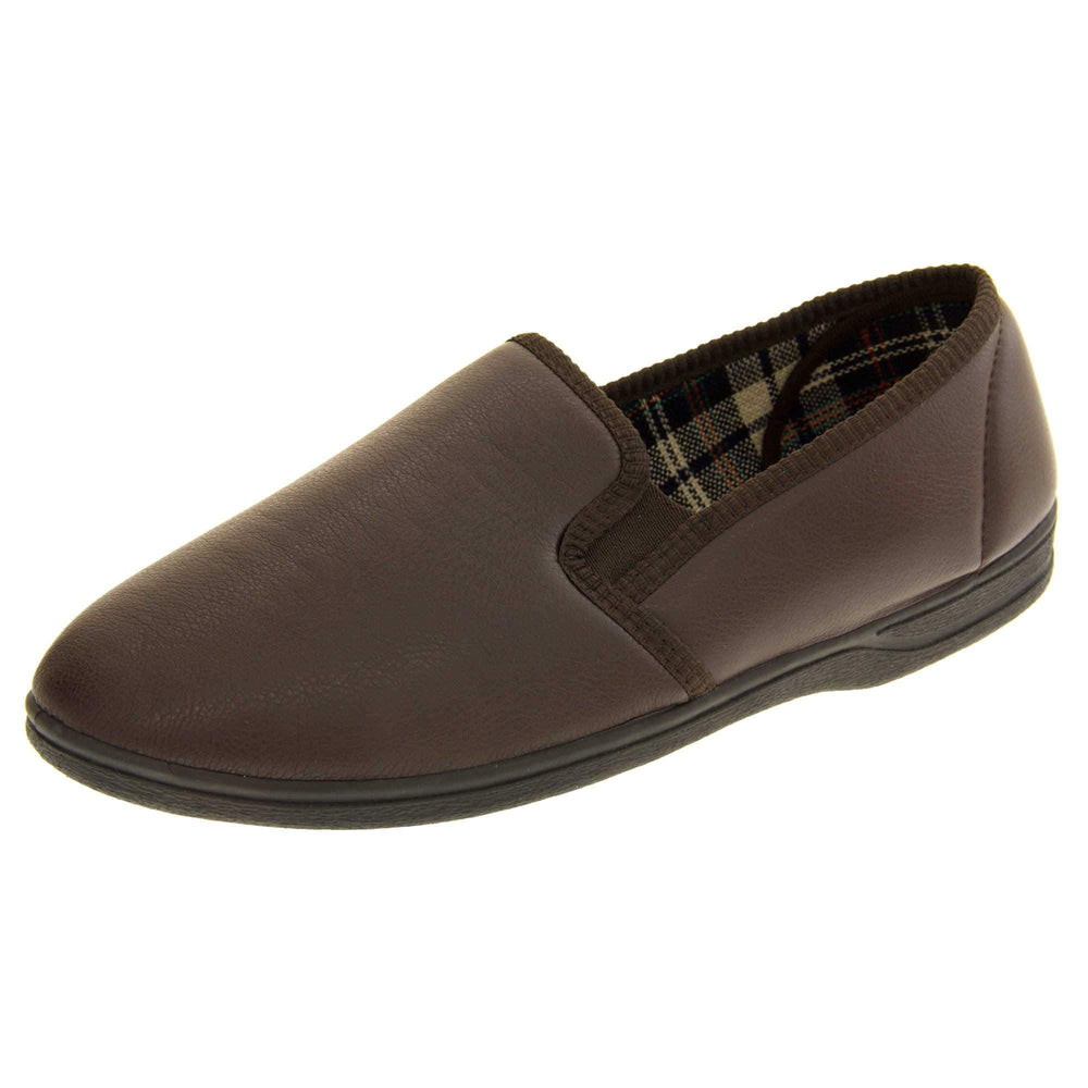 Brown faux leather slippers. Brown faux leather upper with a classic full back slipper design. Twin brown elasticated gussets to the collar of the shoe. Tartan textile lining. Black outdoor sole. Left foot from an angle.