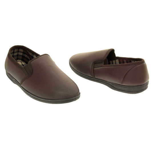 Brown faux leather slippers. Brown faux leather upper with a classic full back slipper design. Twin brown elasticated gussets to the collar of the shoe. Tartan textile lining. Black outdoor sole. Both feet facing top to tail at an angle.