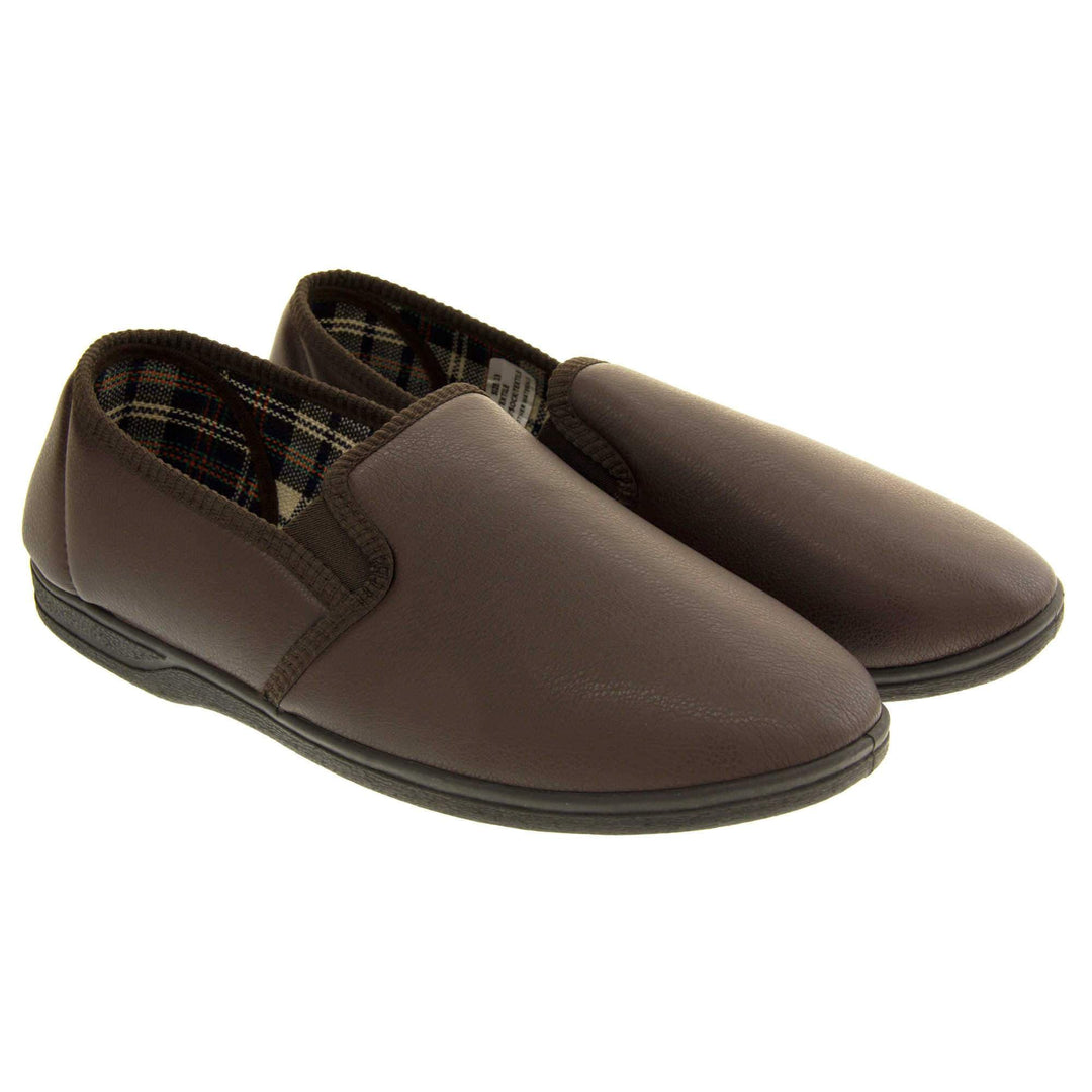 Brown faux leather slippers. Brown faux leather upper with a classic full back slipper design. Twin brown elasticated gussets to the collar of the shoe. Tartan textile lining. Black outdoor sole. Both feet together at an angle.