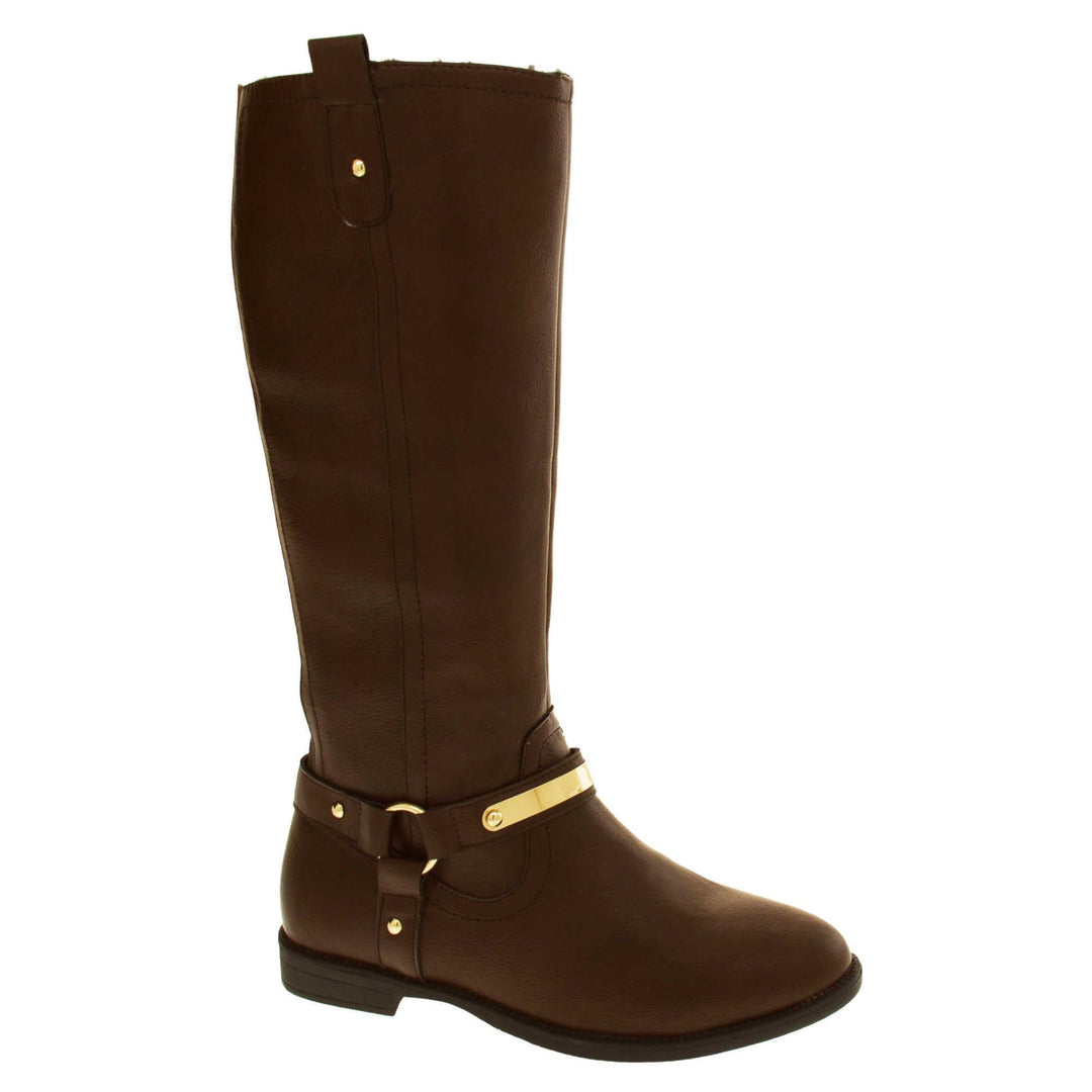 Brown leather boots women. Knee high style boots with a dark brown faux leather upper. A Tri strap going around the ankle and down to the bottom of the boot joined by the ankle with a good loop. Gold plate to the front of the ankle strap. Zip up the inside of the boot. Faux leather loop on the top of the outside of the boot to help with pulling it on. Right foot at an angle.