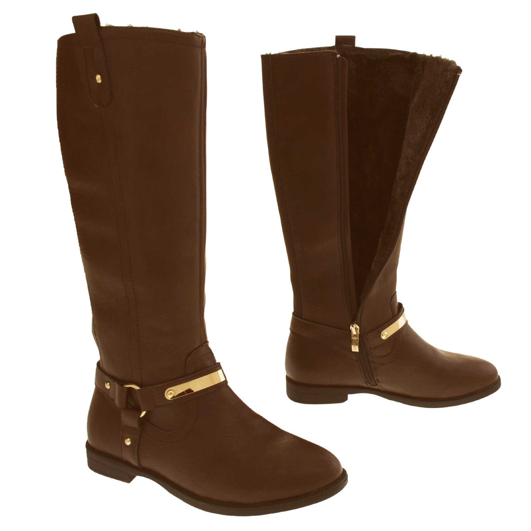 Brown leather boots women. Knee high style boots with a dark brown faux leather upper. A Tri strap going around the ankle and down to the bottom of the boot joined by the ankle with a good loop. Gold plate to the front of the ankle strap. Zip up the inside of the boot. Faux leather loop on the top of the outside of the boot to help with pulling it on. Both feet about a foot apart from the side. Left foot showing the inside of the boot unzipped and the faux fur lining.