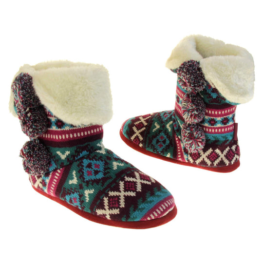 Cable knit slipper boots. Multi coloured patterned knit upper in Aztec style with pom poms to the side, light beige plush faux fur trim and lining. Both feet at an angle, facing top to tail.
