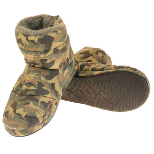 Camo slippers mens. Slipper boots with a camouflage army print textile upper. In khaki, brown, black and sand colours. With a firm black synthetic sole with grip to the base. Grey faux fur lining. Both feet with left foot on its side to show its sole and right foot heel leaning on top of left foot to put it at an angle.