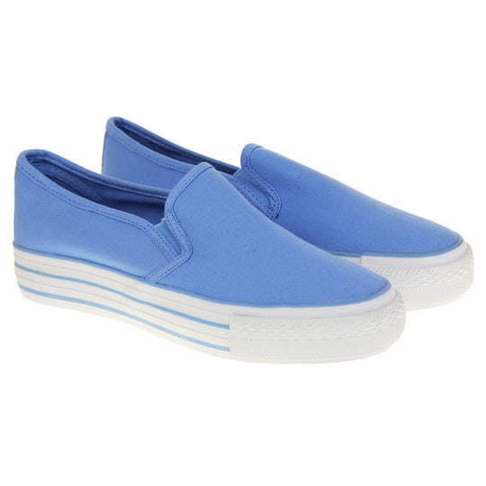 Canvas pumps. Slip on plimsoll style shoes with a blue canvas upper. Blue elasticated gusset. White flat platform sole with two blue lines running around the middle. Both feet together at a slight angle.