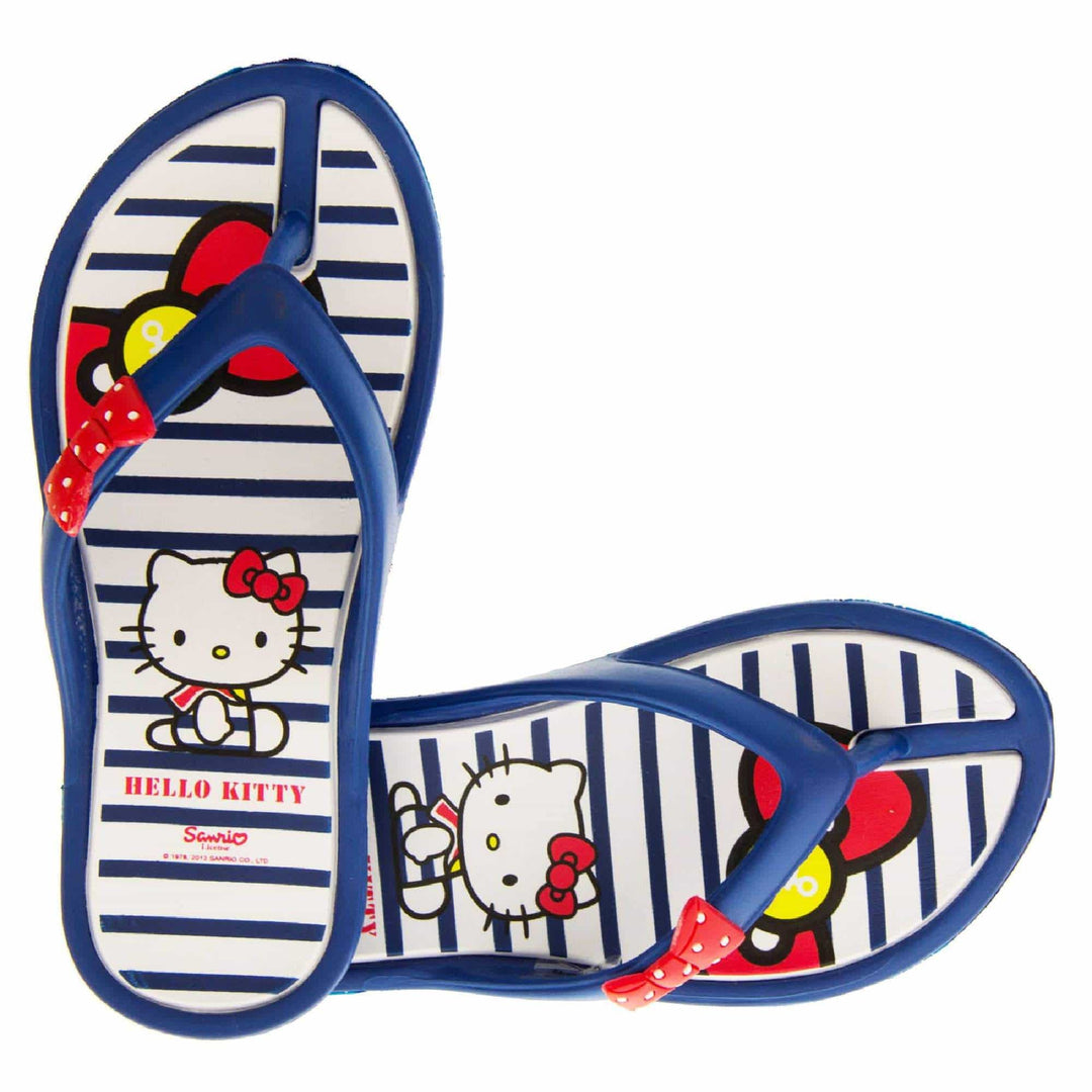 Children's flip flop. Hello Kitty flip flop with navy blue sole and straps in a toe-post design with small red bow with white spots on. White and navy striped insole with Hello Kitty design on. Both feet from a birds eye view with the shoes in an L shape.