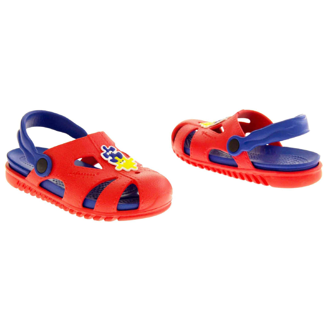 Childrens summers sandals. Fisherman style synthetic sandals with red upper and outer sole. Blue ankle strap and insole. Blue and yellow jigsaw detail to the centre of the upper.  Both shoes at a slight angle facing top to tail.