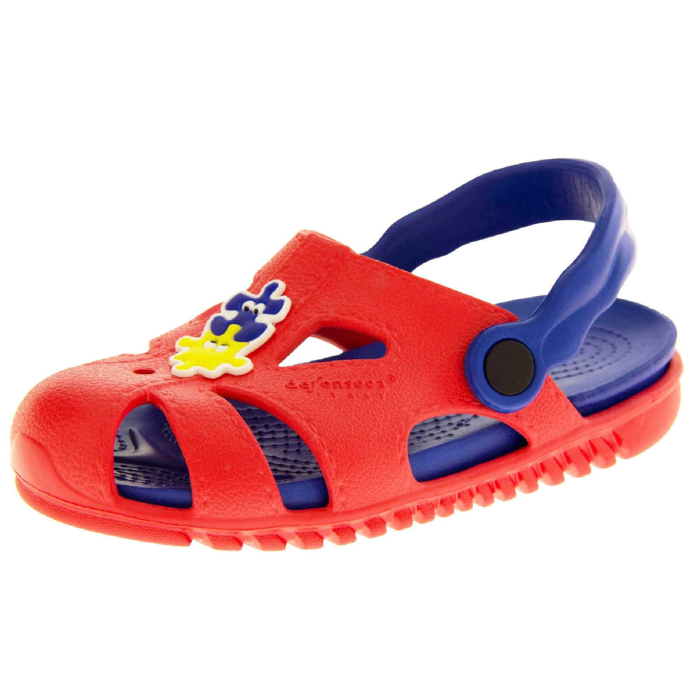 Childrens summers sandals. Fisherman style synthetic sandals with red upper and outer sole. Blue ankle strap and insole. Blue and yellow jigsaw detail to the centre of the upper. Left foot at an angle.