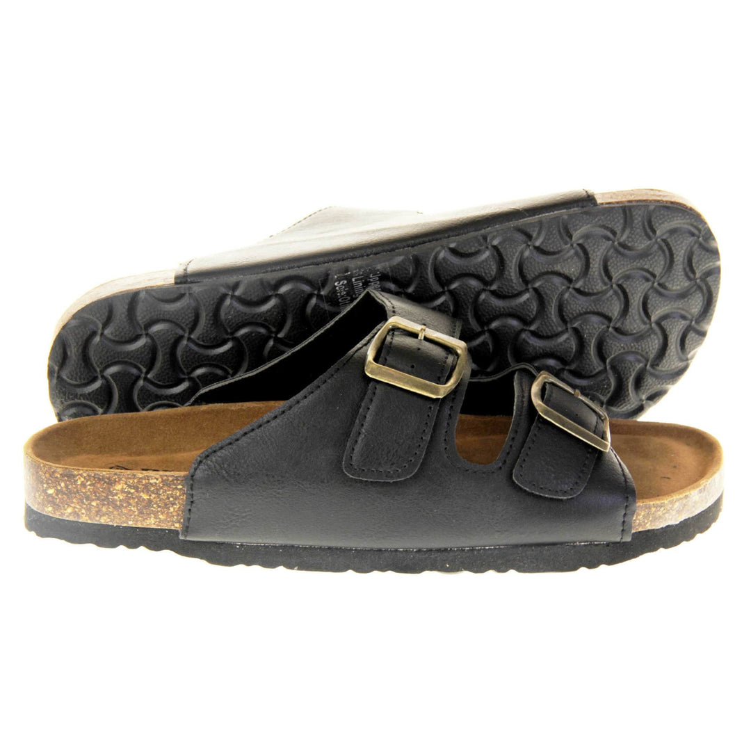 Classic black sandals. Womens dual strap slip on sandals. With a black synthetic leather upper with a gold buckle on each strap. Brown faux suede insole with a moulded footbed. Cork effect outsole with black base with grip to the bottom. Both feet from a side profile with the left foot on its side behind the the right foot to show the sole.