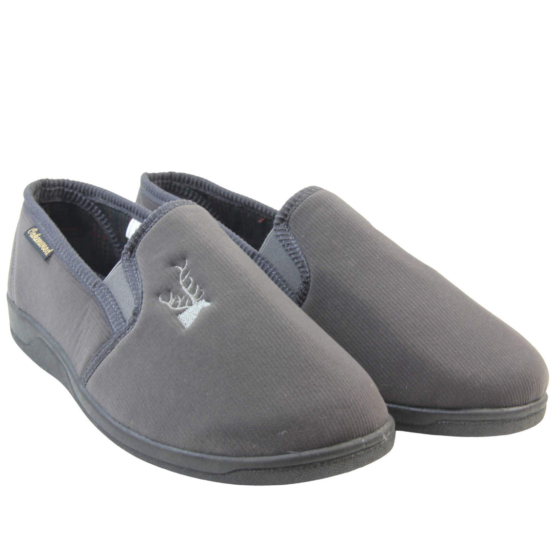 Classic Slippers. Mens full back slippers with a grey velour uppers. Grey elasticated panels joining the tongue to the top of the slippers. Grey stag head detail embroidered onto the top of the upper, near the tongue. Small black label on the outside rim, with Oakenwood branding sewn in gold. Plaid textile lining. Both feet together at an angle.