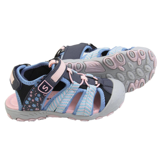 Closed toe girls sandals. Strappy beach sandals with navy mesh and faux leather uppers. With baby blue and pink textile strap detailing. Pink elasticated faux laces to the front. Navy faux leather straps around the front and back of the ankle with touch fastening. Pink insole and grey rubbery outsole and toe bumper with grey and pink grip on the bottom. Both feet from a side profile with the left foot on its side behind the the right foot to show the sole.