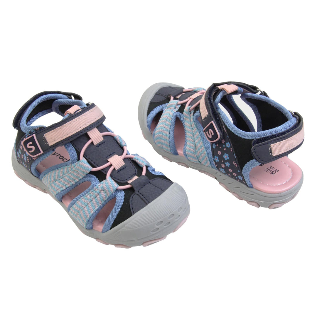 Closed toe girls sandals. Strappy beach sandals with navy mesh and faux leather uppers. With baby blue and pink textile strap detailing. Pink elasticated faux laces to the front. Navy faux leather straps around the front and back of the ankle with touch fastening. Pink and blue flower print detail to the heel sides. Pink insole and grey rubbery outsole and toe bumper with grey and pink grip on the bottom. Both feet at an angle facing top to tail.