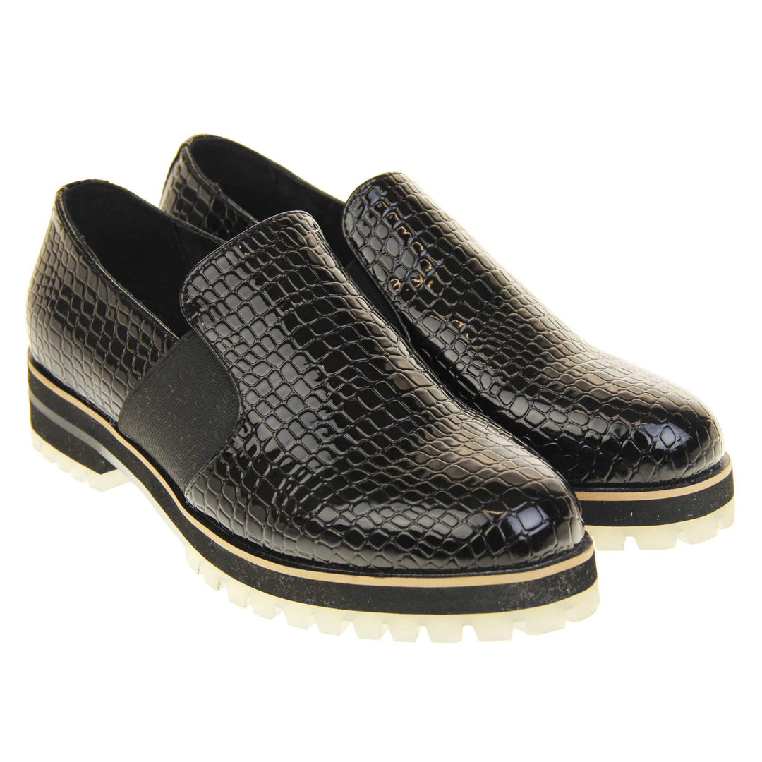 Croc loafers womens. Loafer style shoes with a black faux snakeskin upper. With twin black elasticated side panels. Chunky black and cream sole with slip resistant grip to the bottom. Both feet together at a slight angle.