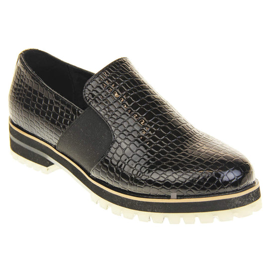 Croc loafers womens. Loafer style shoes with a black faux snakeskin upper. With twin black elasticated side panels. Chunky black and cream sole with slip resistant grip to the bottom. Right foot at an angle.